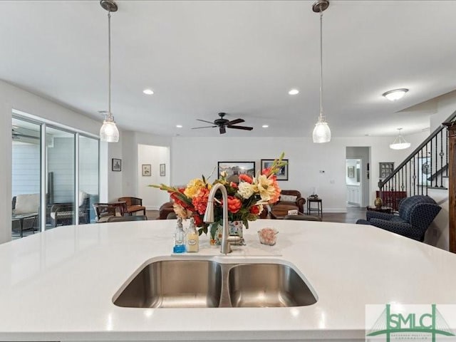 kitchen with sink, a kitchen island with sink, ceiling fan, and decorative light fixtures