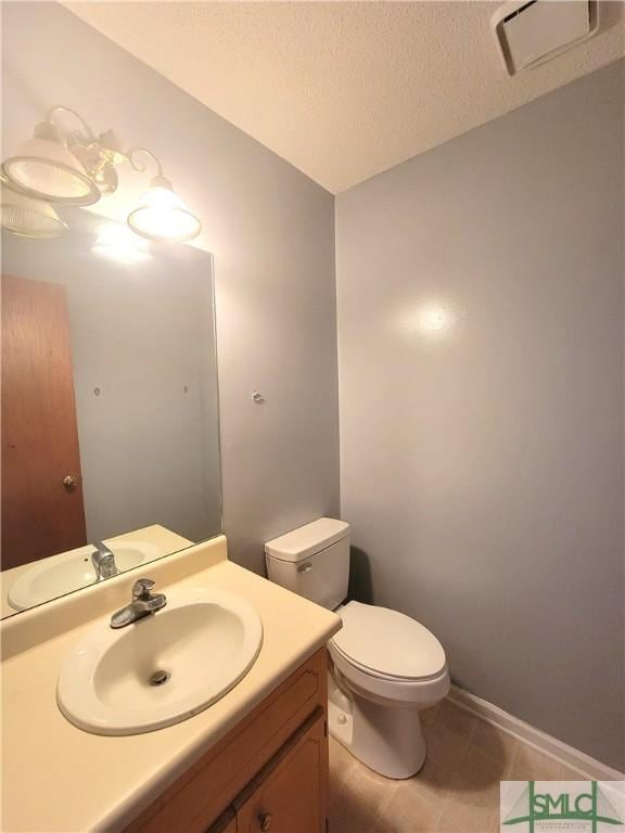 bathroom with vanity, toilet, tile patterned flooring, and a textured ceiling