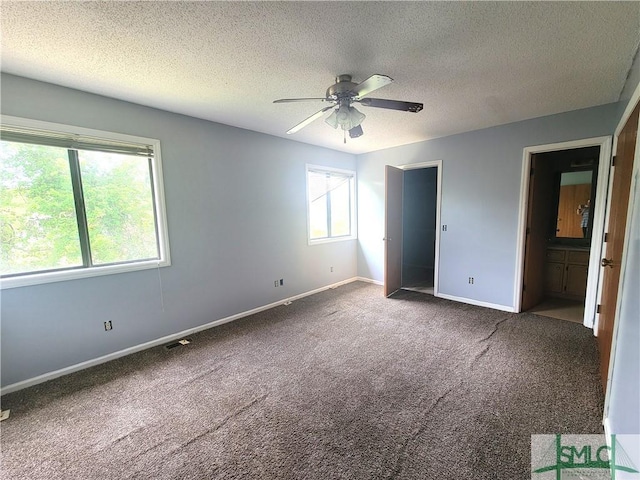 unfurnished bedroom featuring ceiling fan, carpet, a textured ceiling, and ensuite bath