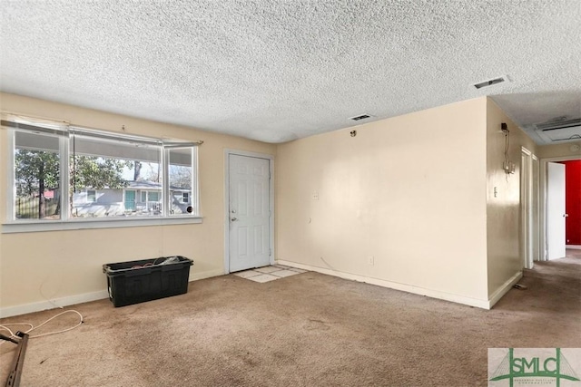 carpeted empty room with a textured ceiling