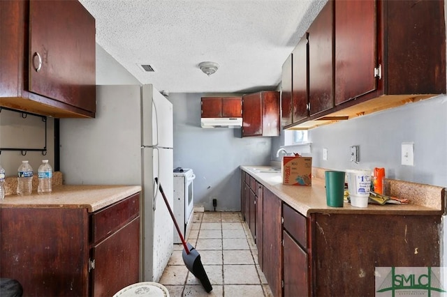 kitchen featuring light tile patterned flooring, sink, white appliances, and a textured ceiling