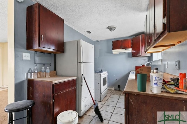 kitchen featuring light tile patterned floors, a textured ceiling, and white appliances