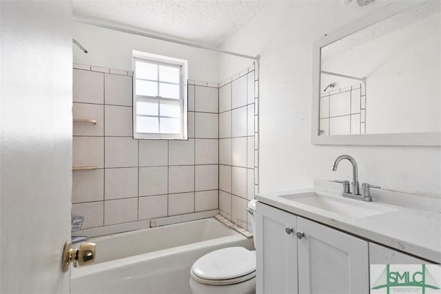 full bathroom featuring tiled shower / bath, vanity, a textured ceiling, and toilet