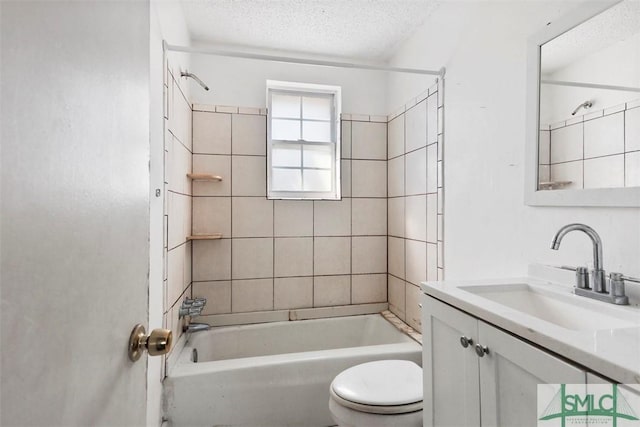 full bathroom with vanity, tiled shower / bath, toilet, and a textured ceiling