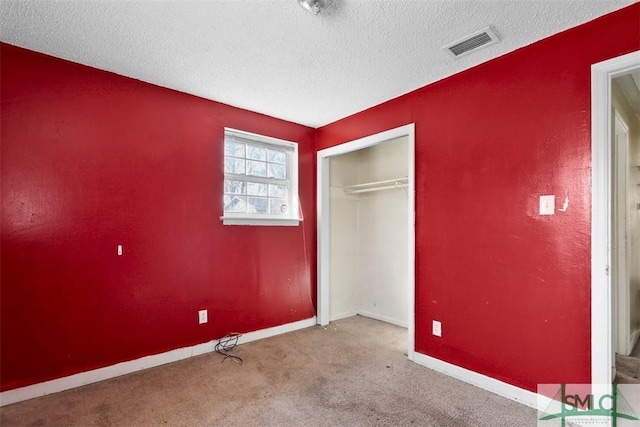 unfurnished bedroom with light colored carpet, a closet, and a textured ceiling