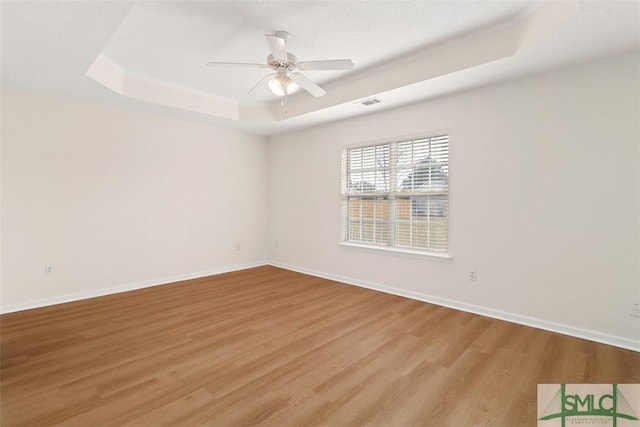 spare room featuring light hardwood / wood-style flooring, a raised ceiling, and ceiling fan