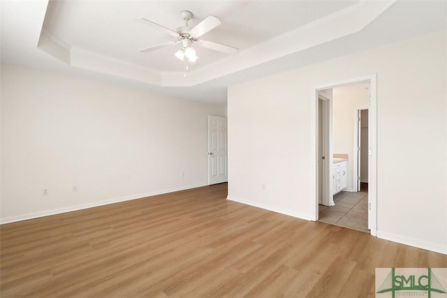 spare room with ceiling fan, light hardwood / wood-style floors, and a tray ceiling