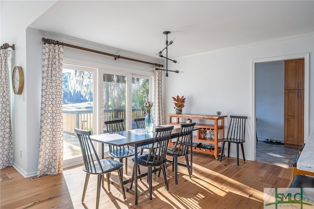 dining room with ornamental molding and light hardwood / wood-style flooring