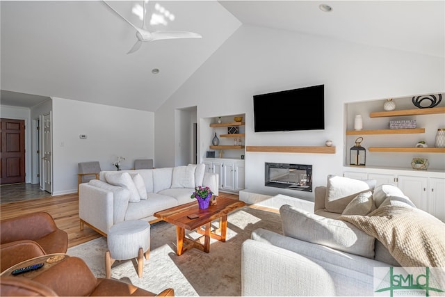 living room with ceiling fan, high vaulted ceiling, and light hardwood / wood-style flooring