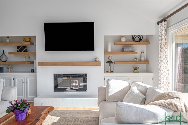 living room with lofted ceiling, built in features, and light hardwood / wood-style floors