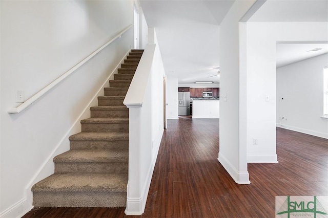 stairway featuring a ceiling fan, visible vents, baseboards, and wood finished floors