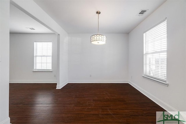 unfurnished room featuring visible vents, baseboards, and dark wood finished floors