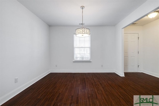 empty room featuring dark wood-style floors, visible vents, and baseboards