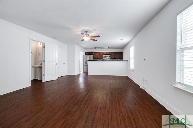 unfurnished living room featuring dark wood-style floors, ceiling fan, and baseboards