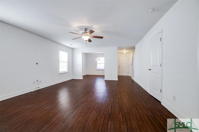 unfurnished living room with ceiling fan, baseboards, and dark wood-style flooring