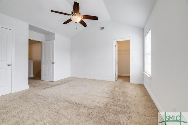 unfurnished bedroom with light carpet, visible vents, lofted ceiling, ceiling fan, and a spacious closet