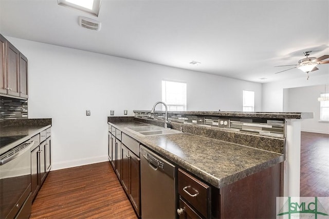 kitchen with a peninsula, dark countertops, black dishwasher, and a sink