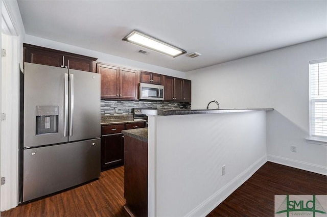 kitchen featuring visible vents, decorative backsplash, dark countertops, dark wood-type flooring, and stainless steel appliances