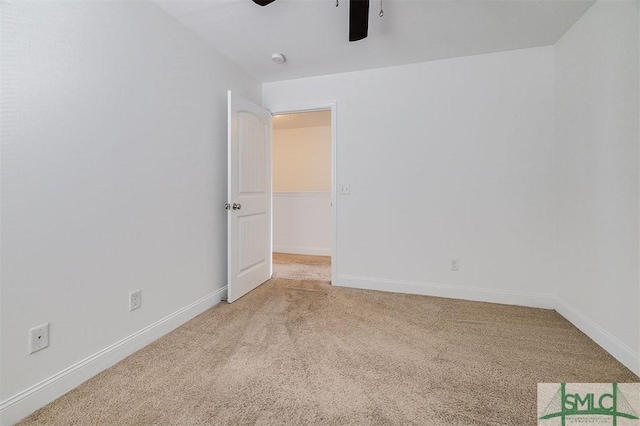 empty room featuring light colored carpet, ceiling fan, and baseboards