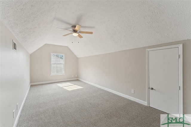 additional living space with ceiling fan, lofted ceiling, carpet flooring, and a textured ceiling