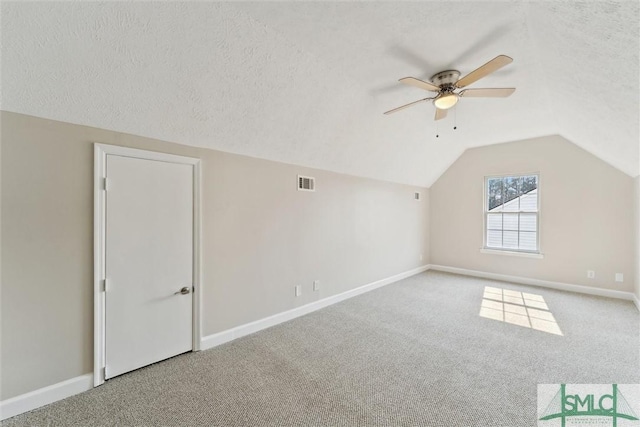 additional living space featuring light carpet, vaulted ceiling, and a textured ceiling