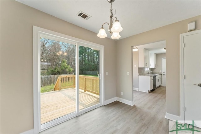 unfurnished dining area with an inviting chandelier, sink, and light wood-type flooring