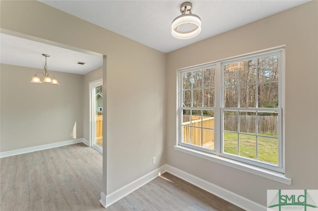 empty room featuring a chandelier and light hardwood / wood-style flooring