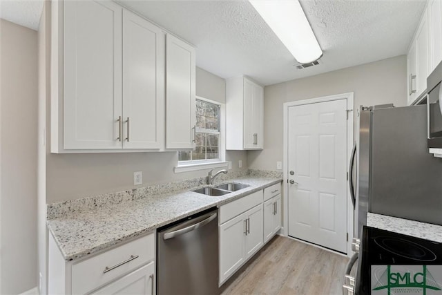 kitchen with sink, white cabinetry, light hardwood / wood-style flooring, stainless steel appliances, and light stone countertops