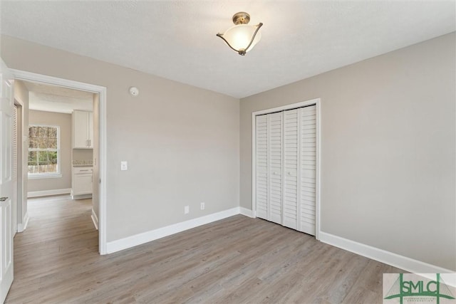 unfurnished bedroom featuring light hardwood / wood-style floors, a closet, and a textured ceiling