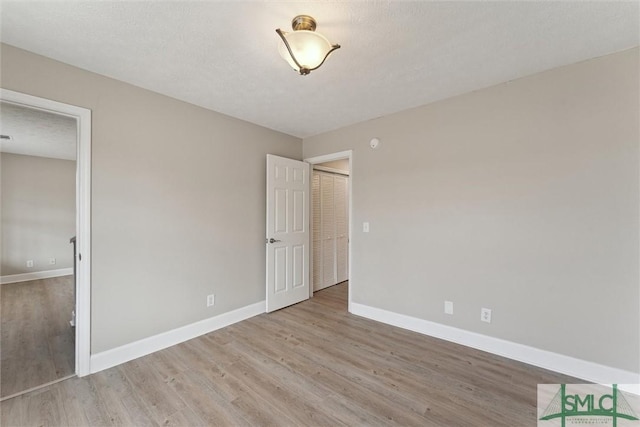 unfurnished bedroom with a textured ceiling and light hardwood / wood-style flooring