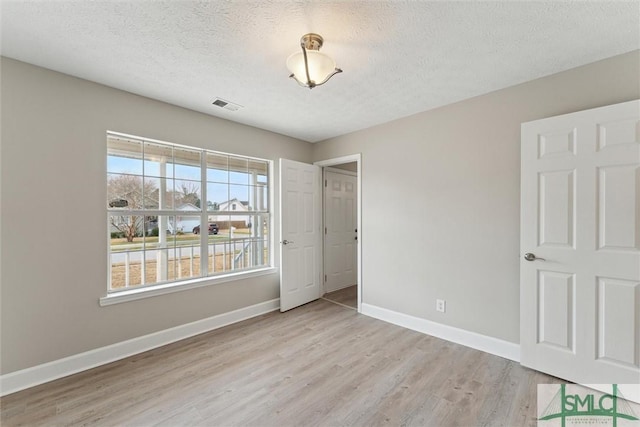 unfurnished bedroom with a textured ceiling and light hardwood / wood-style floors