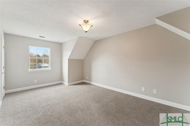 additional living space featuring vaulted ceiling, a textured ceiling, and carpet flooring