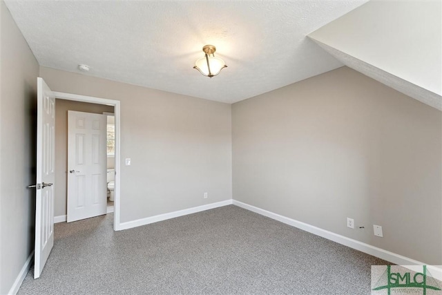 carpeted spare room with vaulted ceiling and a textured ceiling