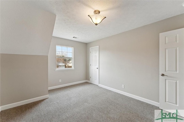 empty room with lofted ceiling, a textured ceiling, and carpet