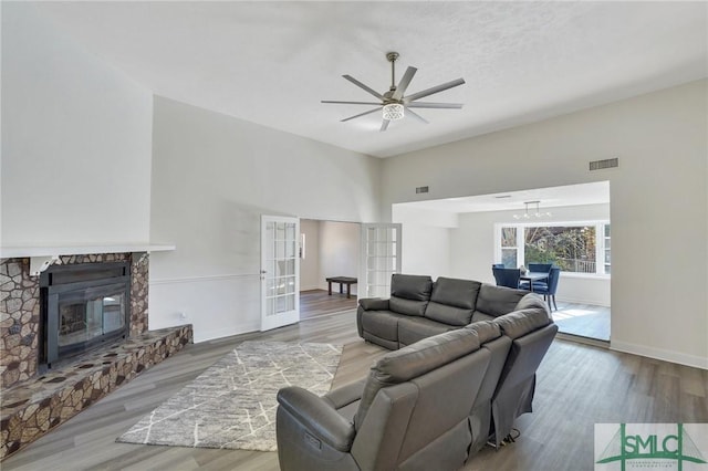 living room featuring a stone fireplace, french doors, ceiling fan, and hardwood / wood-style flooring