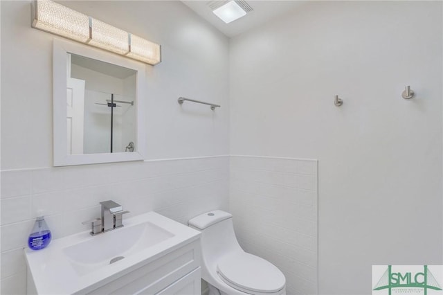 bathroom with vanity, toilet, and tile walls