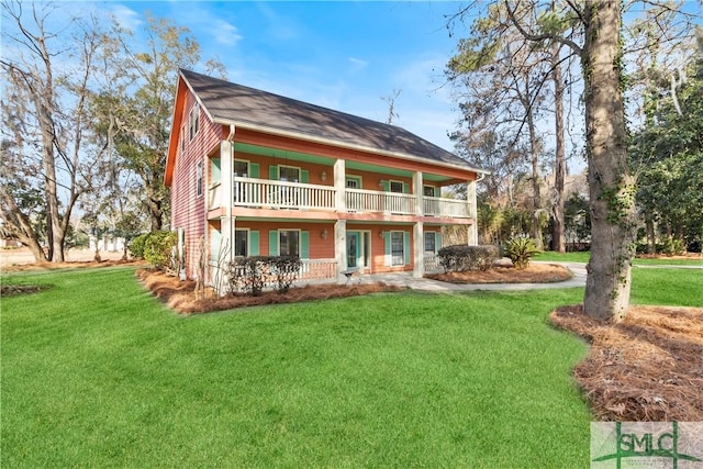 rear view of property featuring a balcony and a yard