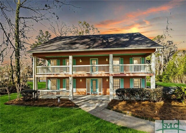 view of front of house with a lawn and a balcony