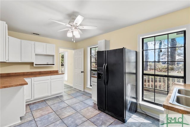 kitchen with visible vents, a sink, white cabinets, ceiling fan, and black refrigerator with ice dispenser