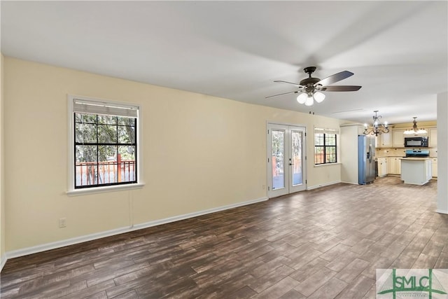 unfurnished living room with dark wood finished floors, ceiling fan with notable chandelier, french doors, and baseboards