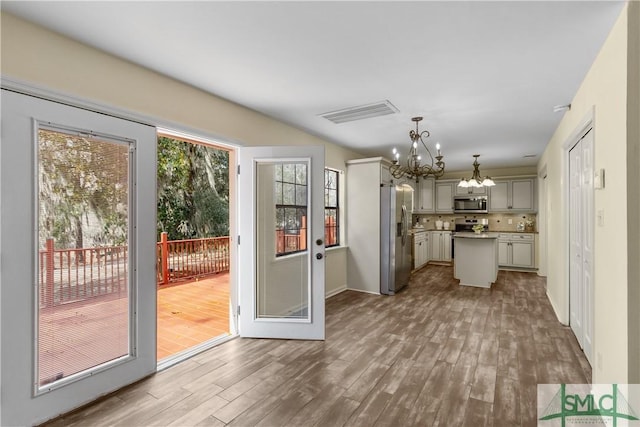 kitchen featuring gray cabinets, decorative light fixtures, a chandelier, a center island, and stainless steel appliances