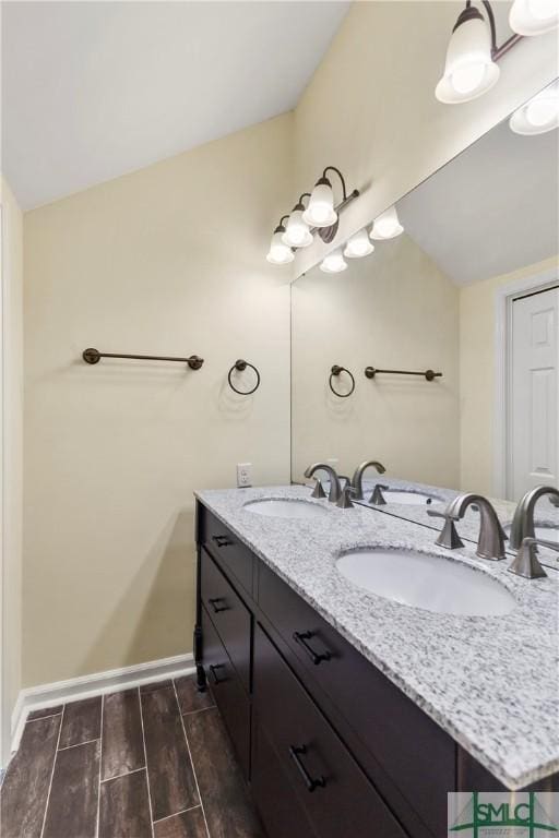 full bath featuring wood tiled floor, baseboards, lofted ceiling, and a sink