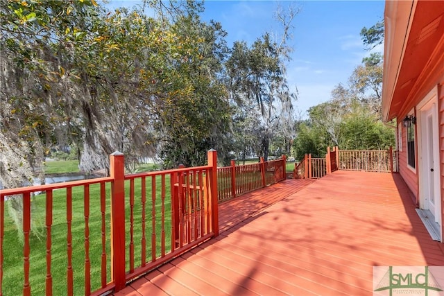 wooden terrace featuring a lawn and a water view