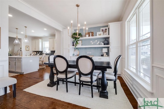 dining room featuring ornamental molding, dark hardwood / wood-style flooring, sink, and a notable chandelier