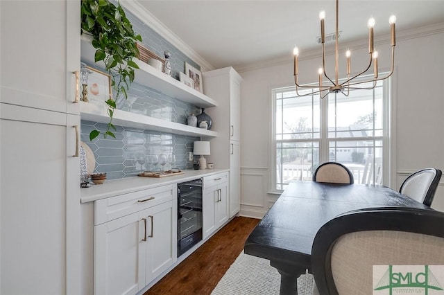 kitchen featuring hanging light fixtures, white cabinetry, beverage cooler, and crown molding