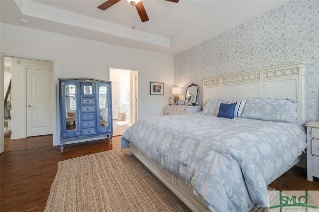 bedroom with ceiling fan, dark hardwood / wood-style flooring, and a tray ceiling