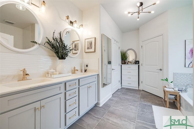 bathroom with vanity, a notable chandelier, and a bathing tub