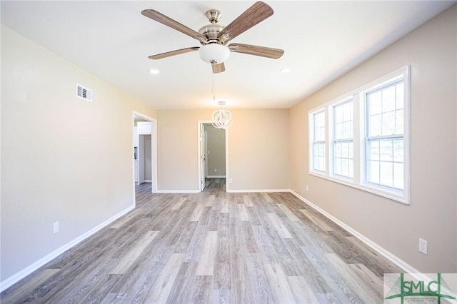 unfurnished room with ceiling fan with notable chandelier and light wood-type flooring