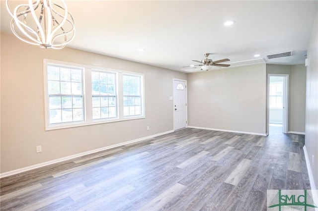 spare room featuring hardwood / wood-style flooring, a wealth of natural light, and ceiling fan with notable chandelier