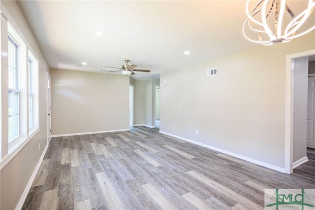 unfurnished room featuring hardwood / wood-style flooring and ceiling fan with notable chandelier